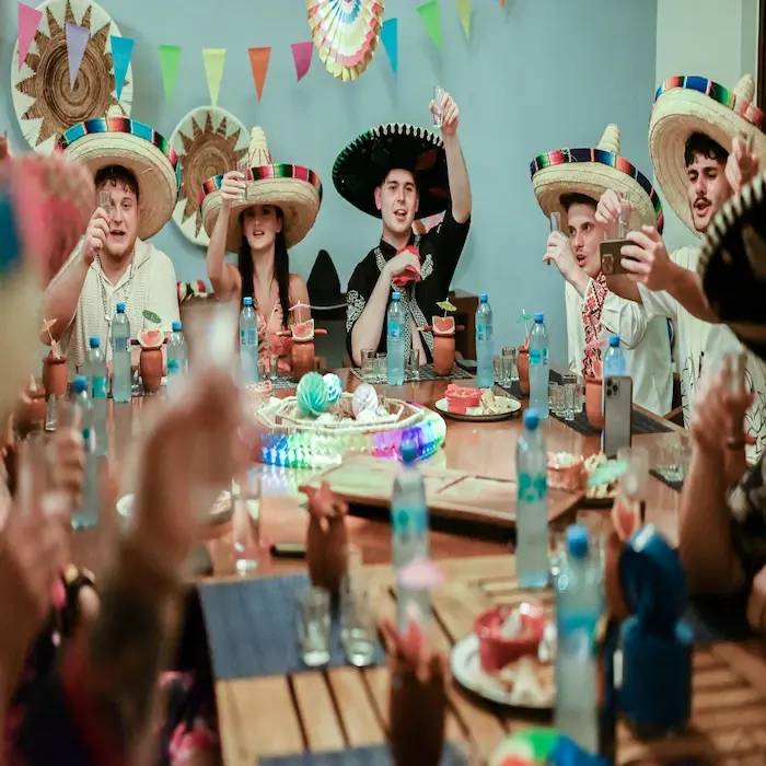 A group of friends pouring tequila for two guests wearing sombreros during a fun tasting experience in Cancun.